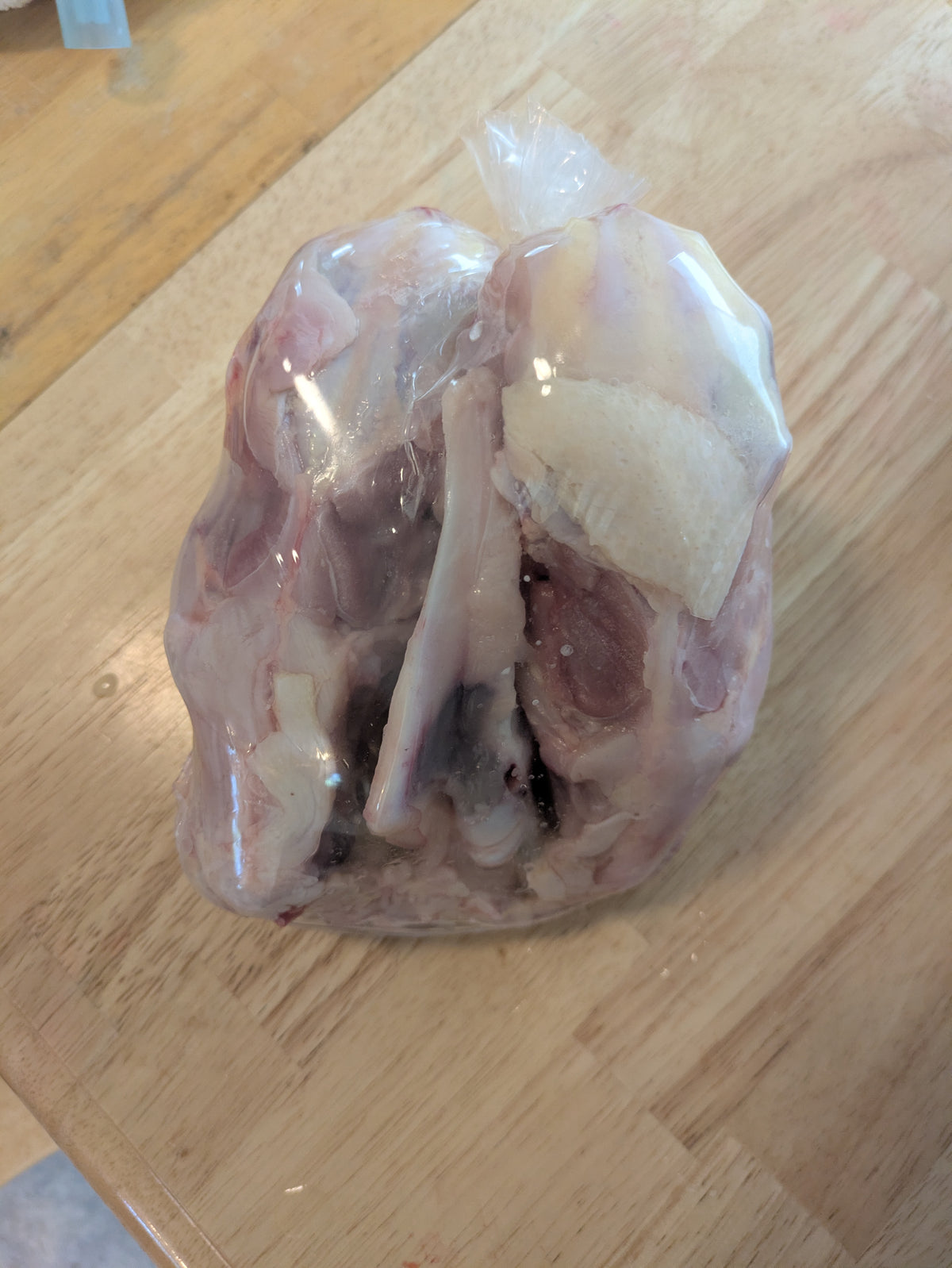 3 chicken carcasses packaged in a plastic bag. Corn free, soy free pasture raised chicken.